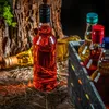 Several bottles of liquid are arranged on a wooden surface with straw and bark in the background. Produktbild-Vorschau