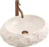 A beige stone-like vessel sink with a bronze faucet. Produktbild-Vorschau