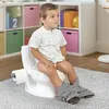 A young boy is sitting on a child-sized toilet with a roll of toilet paper attached. Produktbild-Vorschau