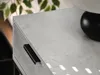 Close-up of a modern console table with a concrete-look finish and a black handle, with a plant in the background. Anteprima dell’immagine prodotto