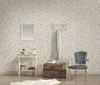 A room with floral wallpaper, a vintage chair, a small table with decorative items, and stacked suitcases. Produktbild-Vorschau