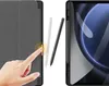 A hand is shown interacting with a tablet case, with two styluses nearby, and a tablet screen visible in the background. Podgląd zdjęcia produktu