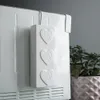 A white radiator with a white heart-shaped water evaporator hanging on it. Voir les images du produit