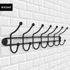 A black metal coat rack with seven hooks mounted on a white tiled wall. Podgląd zdjęcia produktu