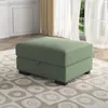 A green ottoman is placed on a patterned rug in a well-lit room with sheer curtains and a window in the background. Produktbild-Vorschau