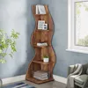 A wooden corner shelf unit filled with books, picture frames, and a plant, placed next to a window and a chair. Produktbild-Vorschau