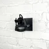 A black spotlight fixture mounted on a white brick wall. Anteprima dell’immagine prodotto