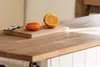 A cutting board with sliced oranges and a knife on a wooden countertop. Anteprima dell’immagine prodotto
