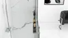 A close-up view of a shower wall with a shower head and a shelf holding two bottles of toiletries. Produktbild-Vorschau
