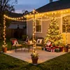 A festive outdoor patio decorated for Christmas with string lights, a Christmas tree, and Santa Claus. Produktbild-Vorschau