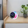 A digital alarm clock with RGB night light is placed on a bedside table next to a potted plant. Produktbild-Vorschau