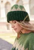 A woman wearing a knitted hat and sweater, with her head tilted down and eyes closed. Produktbild-Vorschau