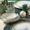 A table setting with plates, bowls, a glass, and candles. Produktbild-Vorschau