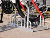 A bicycle parking rack with a bicycle in it, on a paved surface. Produktbild-Vorschau