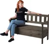 A woman is sitting on a dark gray wooden storage bench. Voir les images du produit