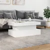 A white coffee table is placed in front of a grey sofa in a living room setting. Voir les images du produit
