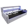 A light gray upholstered bed frame with a slatted mattress support mechanism extended, revealing storage space underneath. Integrated LED lighting illuminates the headboard area. Voir les images du produit