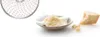 A close-up view of a grater attachment, grated cheese in a bowl, and a wedge of cheese. Produktbild-Vorschau