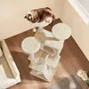 A cat is sleeping on a beige cat tree in a room with wooden floors and a sofa. Produktbild-Vorschau