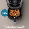 A close-up overhead view of an open air fryer filled with cooked chicken drumsticks and wings, with a blue circle overlay indicating capacity. Náhľad obrázku produktu