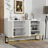 A white sideboard with gold metal legs, featuring open doors revealing shelves with glassware and jars. It is placed in a room with a painting on the wall and a floor lamp. Anteprima dell’immagine prodotto