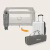 A folded baby travel cot is shown next to a suitcase and a carry bag, with an arrow indicating the cot fits into the bag. Podgląd zdjęcia produktu
