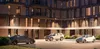 Three cars parked in front of a modern building at night, with exterior lights illuminating the facade. Produktbild-Vorschau