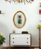 A gold-framed oval mirror hangs above a white dresser with gold knobs. A chandelier is visible above the mirror. Anteprima dell’immagine prodotto