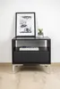 A black nightstand with a framed picture and a small plant on top, placed against a white wall. Produktbild-Vorschau
