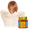 A person is massaging their neck while a jar of Tiger Balm is placed next to them. Podgląd zdjęcia produktu