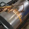 A metal barrel is being laser cut with a logo and text. Produktbild-Vorschau
