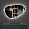 A modern bathroom vanity with a sink and a large, irregularly shaped mirror with integrated LED lighting. Anteprima dell’immagine prodotto