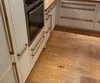 A modern kitchen with light-colored cabinets and wood flooring, featuring an oven and drawers. Produktbild-Vorschau