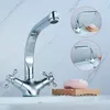 A chrome faucet with two handles sits on a white sink against a marble-patterned wall. Two circular insets show the faucet from different angles, one with a bar of soap on a wooden holder. Náhled obrázku produktu
