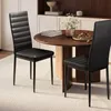 Two black dining chairs are placed around a round wooden dining table in a well-lit room. Náhled obrázku produktu