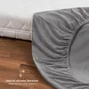 A close-up of a gray fitted sheet draped over a mattress, with a portion of the mattress visible in the background. Produktbild-Vorschau