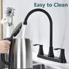 A hand is holding the lid of a stainless steel electric kettle while water is being poured into it from a black faucet in a kitchen setting. Produktbild-Vorschau