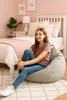 A young girl sits on a beanbag in a bedroom. Anteprima dell’immagine prodotto
