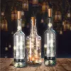 Three glass bottles with LED string lights inside, placed on a wooden surface with a blurred background of hanging lanterns. Anteprima dell’immagine prodotto