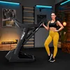 A woman posing next to a treadmill in a home gym setting. Produktbild-Vorschau