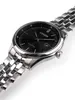 A close-up, angled shot of a men's wristwatch with a black dial and silver metal band, set against a white background. Podgląd zdjęcia produktu