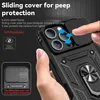 A hand holding a black iPhone case with a sliding camera cover and a ring stand. Produktbild-Vorschau
