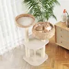 A cat is relaxing on a cat tree in a well-lit room with a dresser and plants in the background. Anteprima dell’immagine prodotto