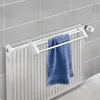 A blue towel is hanging on a white towel rack attached to a white radiator, with gray tiled walls in the background. Náhled obrázku produktu
