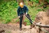 A person rappelling down a rocky cliff face with green foliage in the background. Produktbild-Vorschau