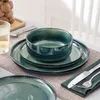 A table setting with green ceramic dishes, a glass of water with lemon, and a jar of walnuts in the background. Náhled obrázku produktu