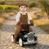 A baby is sitting on a black ride-on car on a cobblestone path. Náhled obrázku produktu