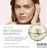 A woman's face and a jar of cream are shown. Voir les images du produit