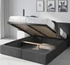 A bed with its storage compartment open, revealing the slatted base and internal space. The bed is upholstered in dark gray fabric. Produktbild-Vorschau
