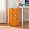 An orange filing cabinet with five drawers is placed next to a white desk. The cabinet has silver handles and is on wheels. There are books and a bust on top of the cabinet, and a vase with flowers and a computer monitor on the desk. Voir les images du produit